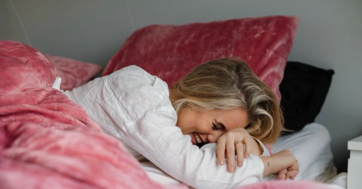 De vrouw ontspant in onze zachte, roze velvet dekbedovertrek, omringd door luxe en comfort. Haar glimlach weerspiegelt de serene sfeer terwijl het warme materiaal haar omhult. Een perfect moment van rust en zelfzorg! foto: banner meisje.