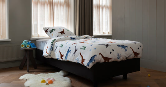 Een zacht velvet dekbedovertrek met een dino-print, geplaatst op een bed in een lichte slaapkamer. De stof heeft een luxueuze uitstraling en accentueert de gezellige sfeer van de ruimte, omgeven door neutrale tinten en natuurlijke lichtinval.
foto: dino dekbedovertrek eenpersoons kinderkamer