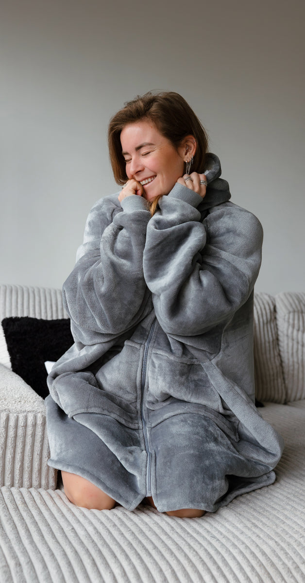 Een meisje in een grijze xxl hoodie met capuchon, genietend van haar comfortabele outfit. De hoodie is gemaakt van ultrazacht velvet en is gevoerd met sherpa, waardoor het perfect is om te relaxen. Het is een 'one size fits all' model dat gezelligheid en stijl combineert.
foto: hoodie grijs met vrouw