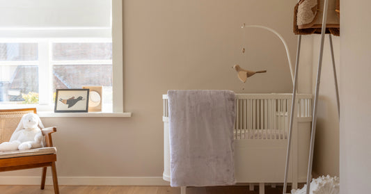 Een taupe velvet dekbedovertrek hangt elegant over een ledikantje in een sfeervolle babykamer. De zachte textuur van het dekbedovertrek is zichtbaar, en de kleuren van de kamer zijn warm en uitnodigend. 
foto: ledikant dekbedovertrek taupe kinderkamer