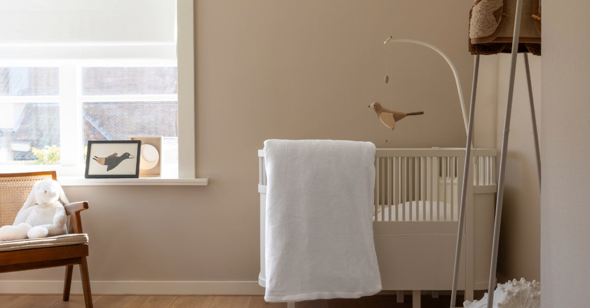 Een elegant wit velvet dekbedovertrek voor een ledikant, zachtjes hangend over de rand van een stijlvol ingericht babykamertje. Het dekbedovertrek voegt een luxe uitstraling toe aan de ruimte, omringd door neutrale kleuren en schattige decoraties die een warme en uitnodigende sfeer creëren voor een baby.
foto: ledikant dekbedovertrek wit kinderkamer