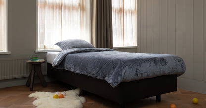 Zacht grijs velvet dekbedovertrek voor peuters, perfect voor een comfortabele en stijlvolle slaapomgeving. Het dekbedovertrek heeft een luxueuze, fluweelachtige textuur en is speciaal ontworpen voor de gevoeligere huid van jonge kinderen. foto: peuter dekbedovertrek grijs op bed.