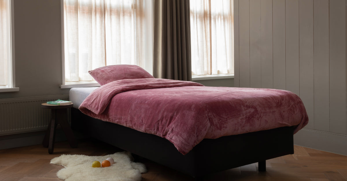 Een eenpersoonsbed mooi opgemaakt met een roze velvet dekbedovertrek, dat er heerlijk zacht uitziet. De luxueuze stof en de zachte uitstraling nodigen uit om er comfortabel in te liggen.
foto: roze dekbedovertrek eenpersoons