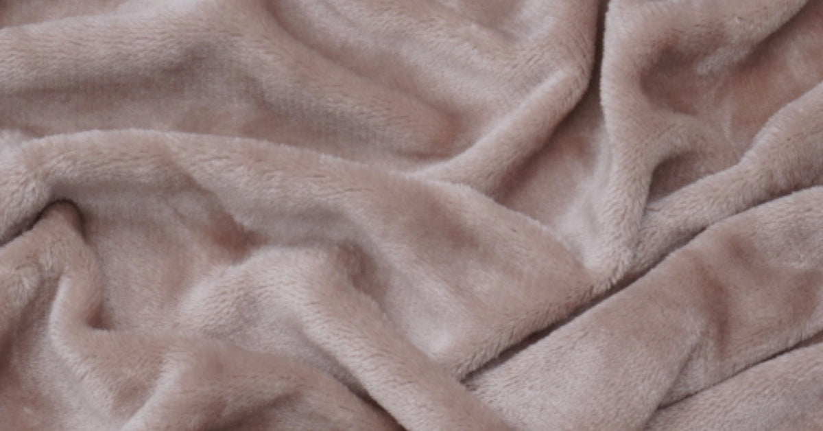 Close-up shot of a taupe velvet toddler duvet cover fabric, showing the soft, plush texture and rich color of the material. The surface has a subtle sheen, giving the velvet a luxurious appearance. foto: stof dekbedovertrek peuter taupe.